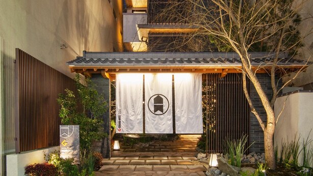 A traditional Japanese gate with a wooden structure and a white banner. - GRAND BASE Osu (Nagoya)