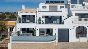 A modern two-story house with a balcony, large windows, and a garage.