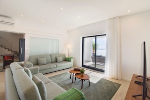 A modern living room with a sofa, two side tables, and a TV. - Villa Albufeira 78, villa with sea view for 12 people (Albufeira)