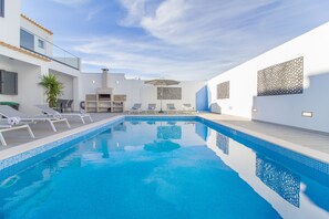 A modern indoor swimming pool with lounge chairs and a glass balustrade.