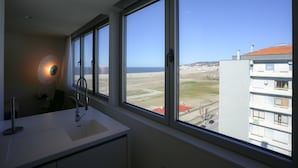 Ein Badezimmer mit großem Fenster, einem Waschbecken und einem Spiegel.