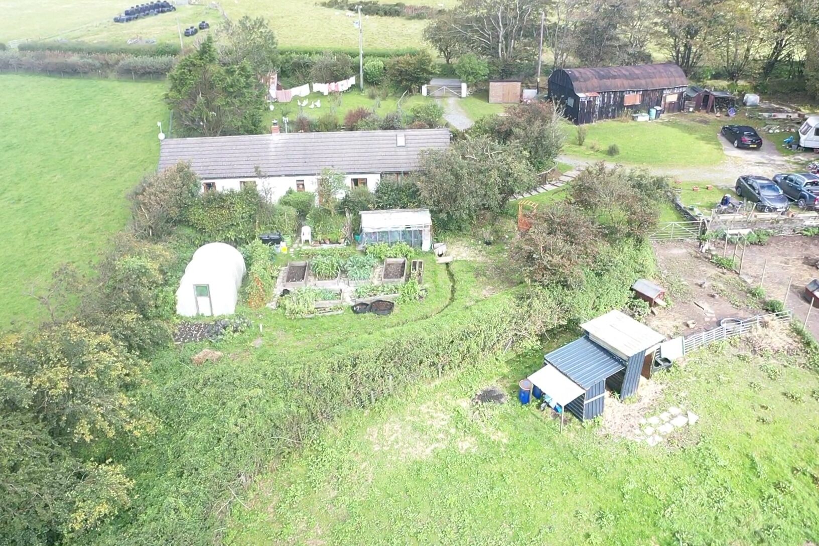 Una propiedad rural con una casa grande, varias construcciones adicionales y un jardín.