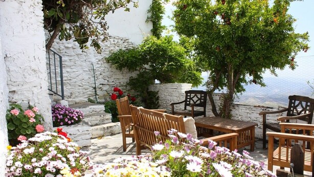 An outdoor seating area with wooden furniture and a stone wall backdrop. - Las Chimeneas (Nevada)