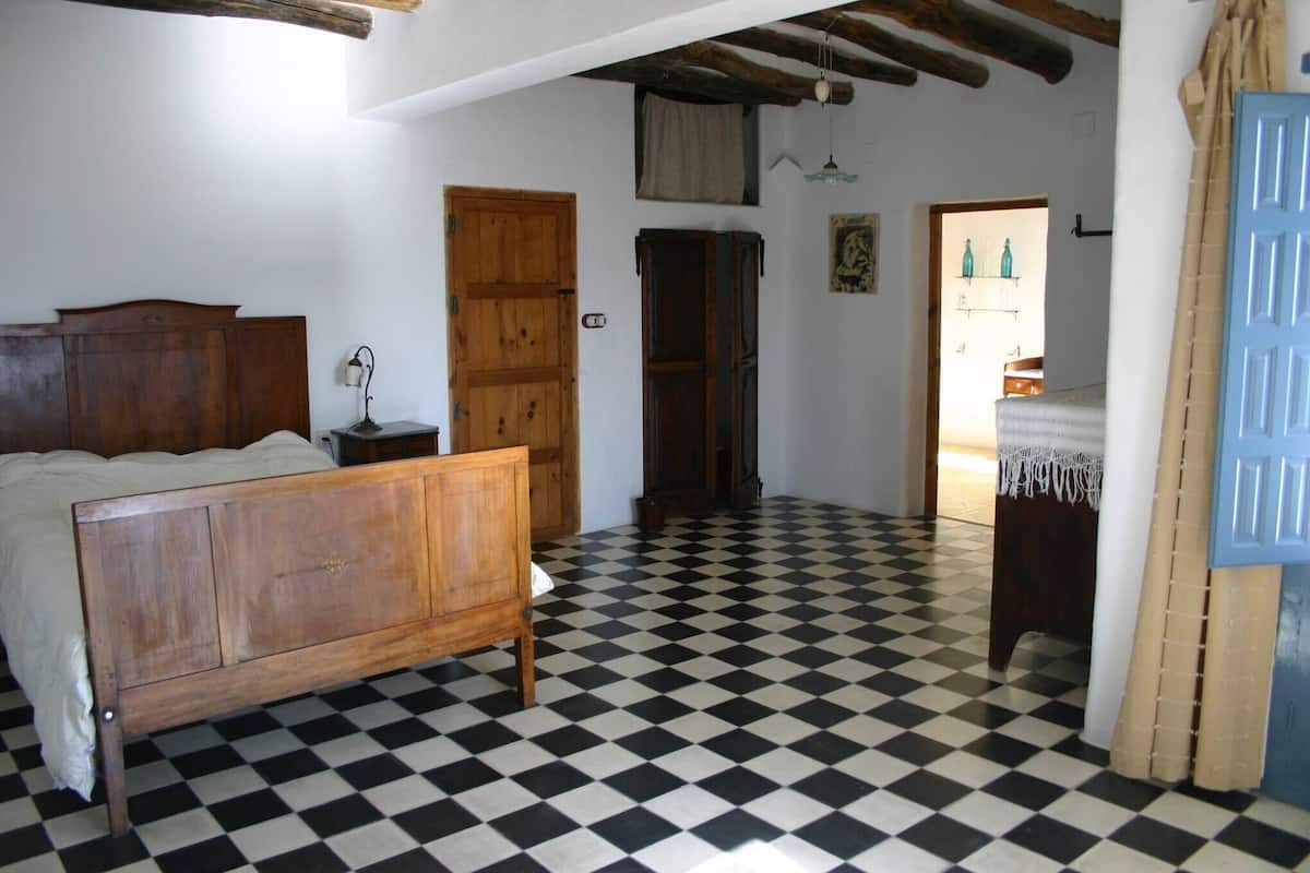 A bedroom with a wooden bed, a checkered floor, and a blue door.