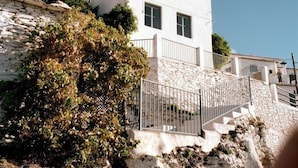 A white building with a stone facade, a balcony, and a staircase leading up to the entrance. - Las Chimeneas (Nevada)
