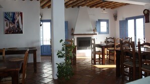 A dining area with wooden furniture and a tiled floor, a fireplace, and a painting on the wall. - Las Chimeneas (Nevada)