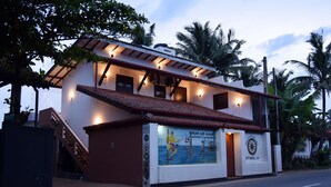 A two-story building with a tiled roof and a mural depicting a traditional scene. - Wagon Wheel Inn - Hostel (Boossa)