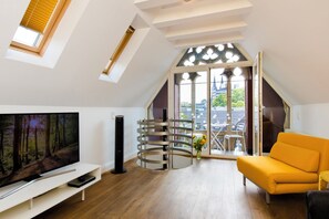 Un appartement moderne de style « loft », doté d’une grande verrière, d’un téléviseur, d’un escalier en colimaçon et d’un canapé jaune.