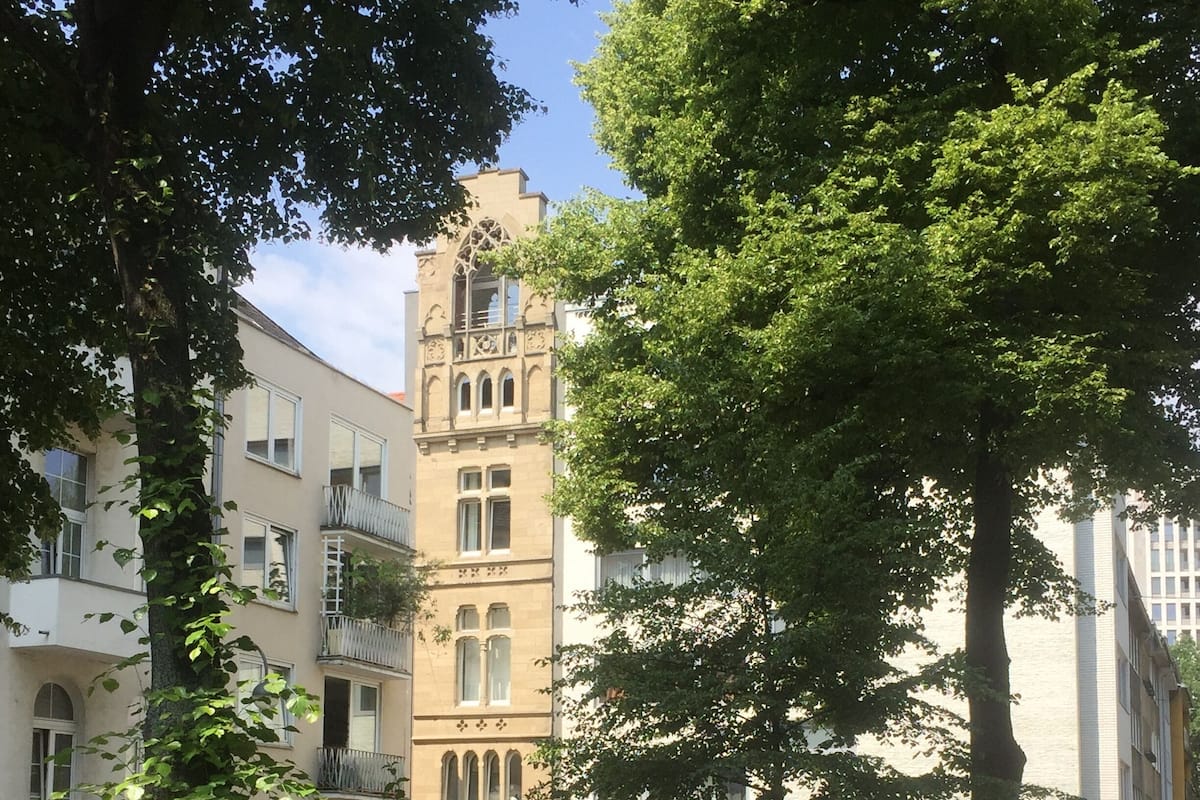 Un bâtiment doté d’une tour, entouré d’arbres et de verdure.