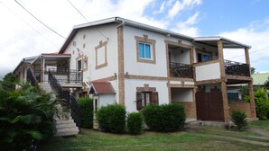 A two-story house with a balcony, a staircase, and a small garden area. - Apartment for 2 people  (La riviere saint louis)