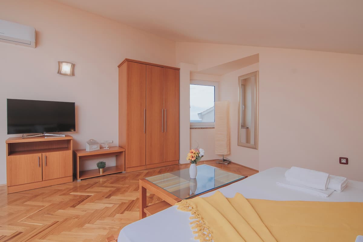 Una habitación de hotel moderna con una cama grande, un televisor de pantalla plana, muebles de madera y una ventana con vistas.