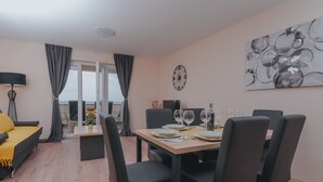 Un espace de salle à manger moderne avec une table en bois dressée pour six personnes, des chaises noires et un grand tableau abstrait accroché au mur.