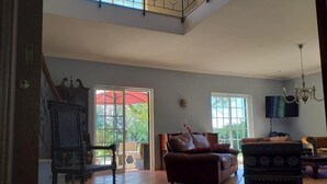 A spacious living room with a high ceiling, large windows, and a mix of traditional and modern furniture. - Casa dos Ventos (Olhao)