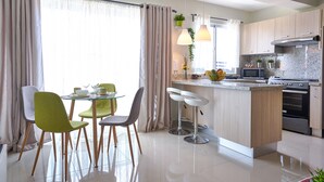 Une cuisine moderne dotée d’un îlot central, d’un coin repas avec des chaises et d’une grande fenêtre agrémentée de rideaux.
