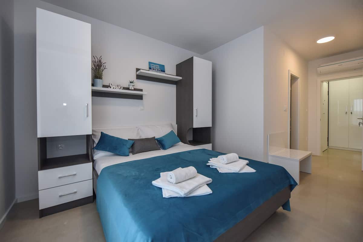 Een moderne slaapkamer met een groot bed, een inbouwkast en een klein zithoekje.