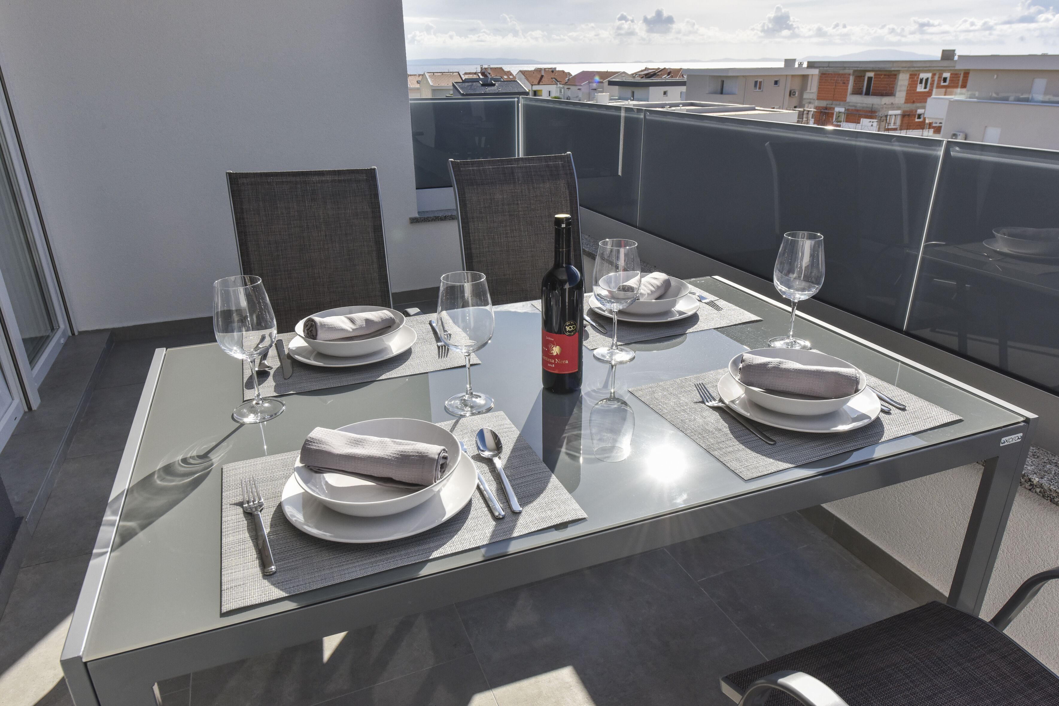 Mesa de comedor para cuatro en un balcón con vista despejada al paisaje urbano.
