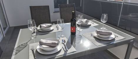 Mesa de comedor para cuatro en un balcón con vista despejada al paisaje urbano.
