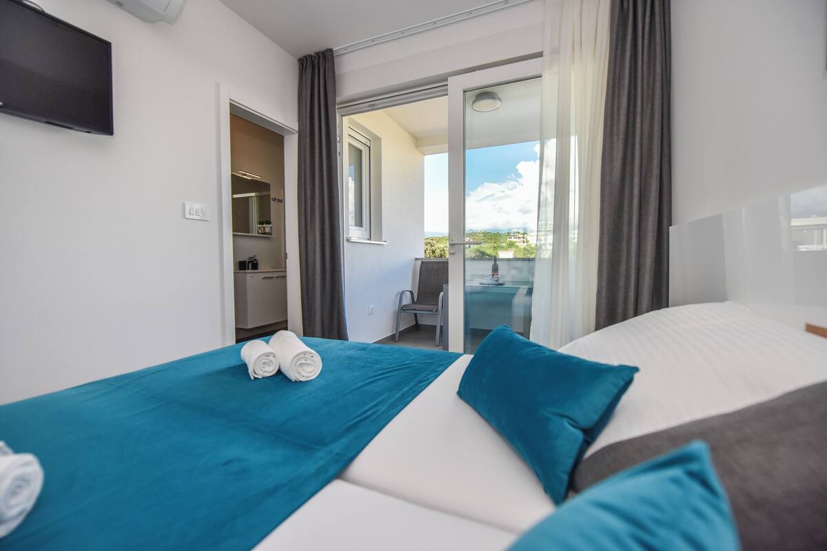 Een hotelkamer met een bed, een bureau, een stoel en een badkamer, zichtbaar door een open deur.