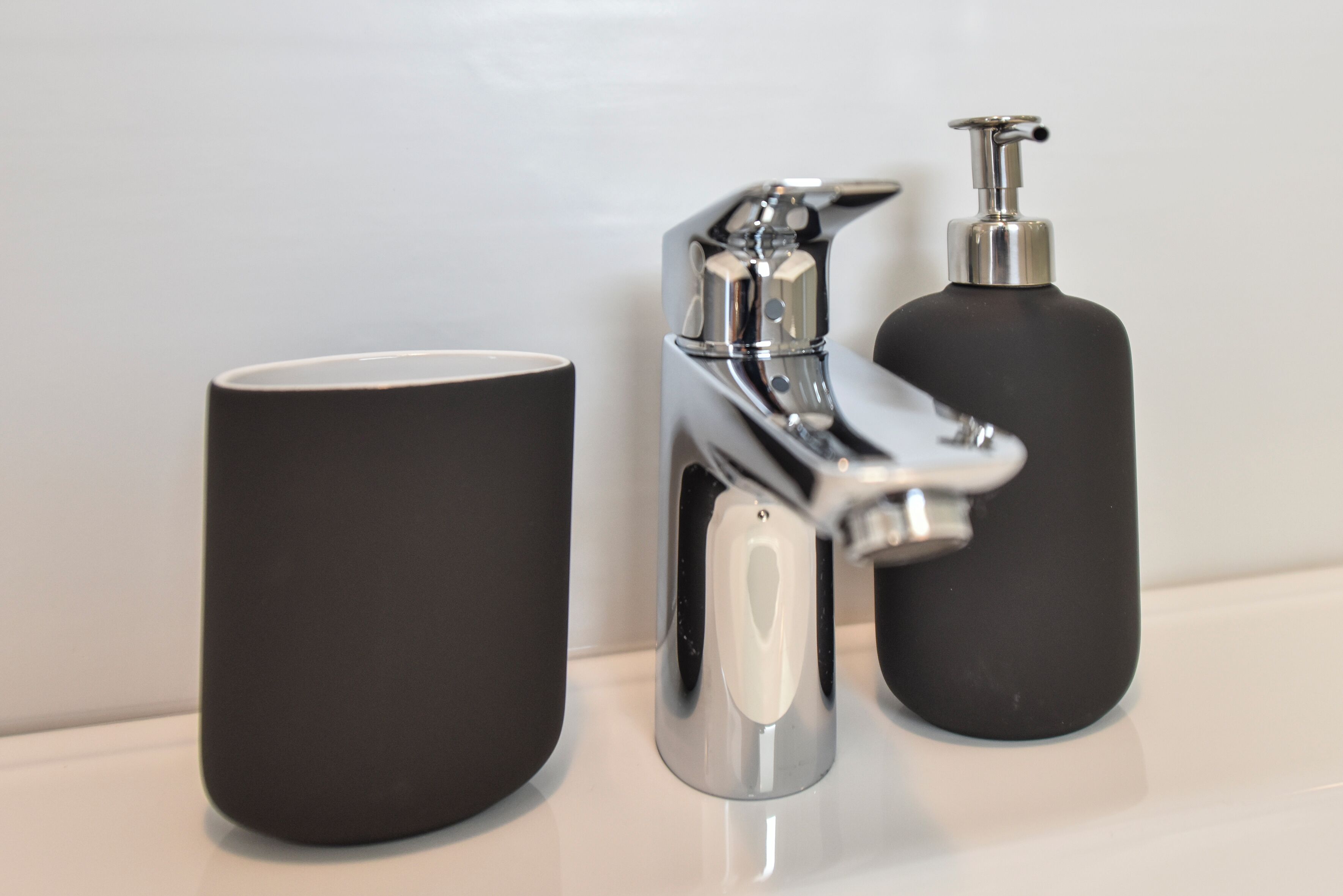 A bathroom sink with a chrome faucet and a black soap dispenser.