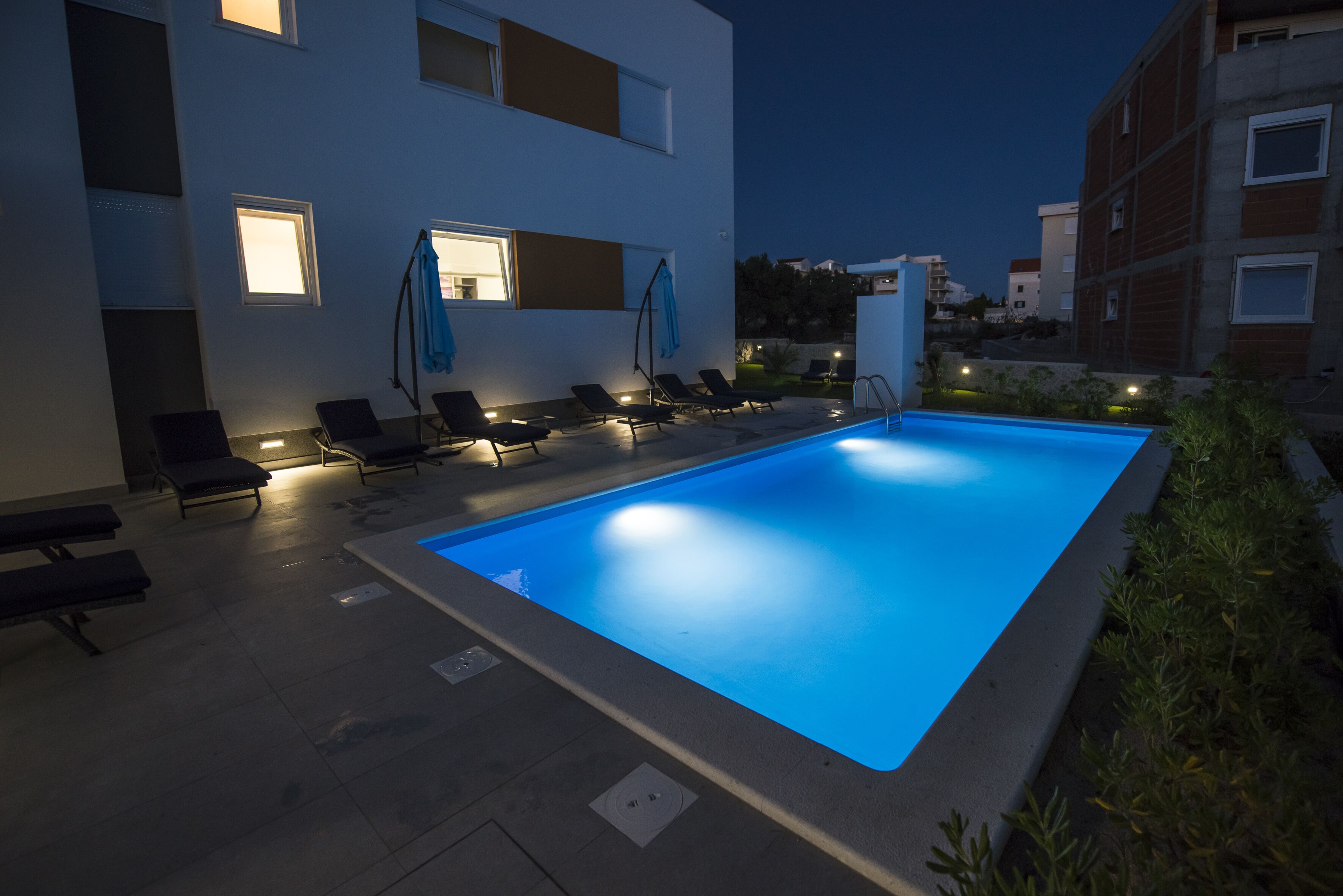 A swimming pool area with lounge chairs and a modern building in the background.
