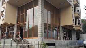 A modern building with large windows, a staircase, and a gated entrance. - Sodere Resort Hotels Africa Union (Addis Ababa)