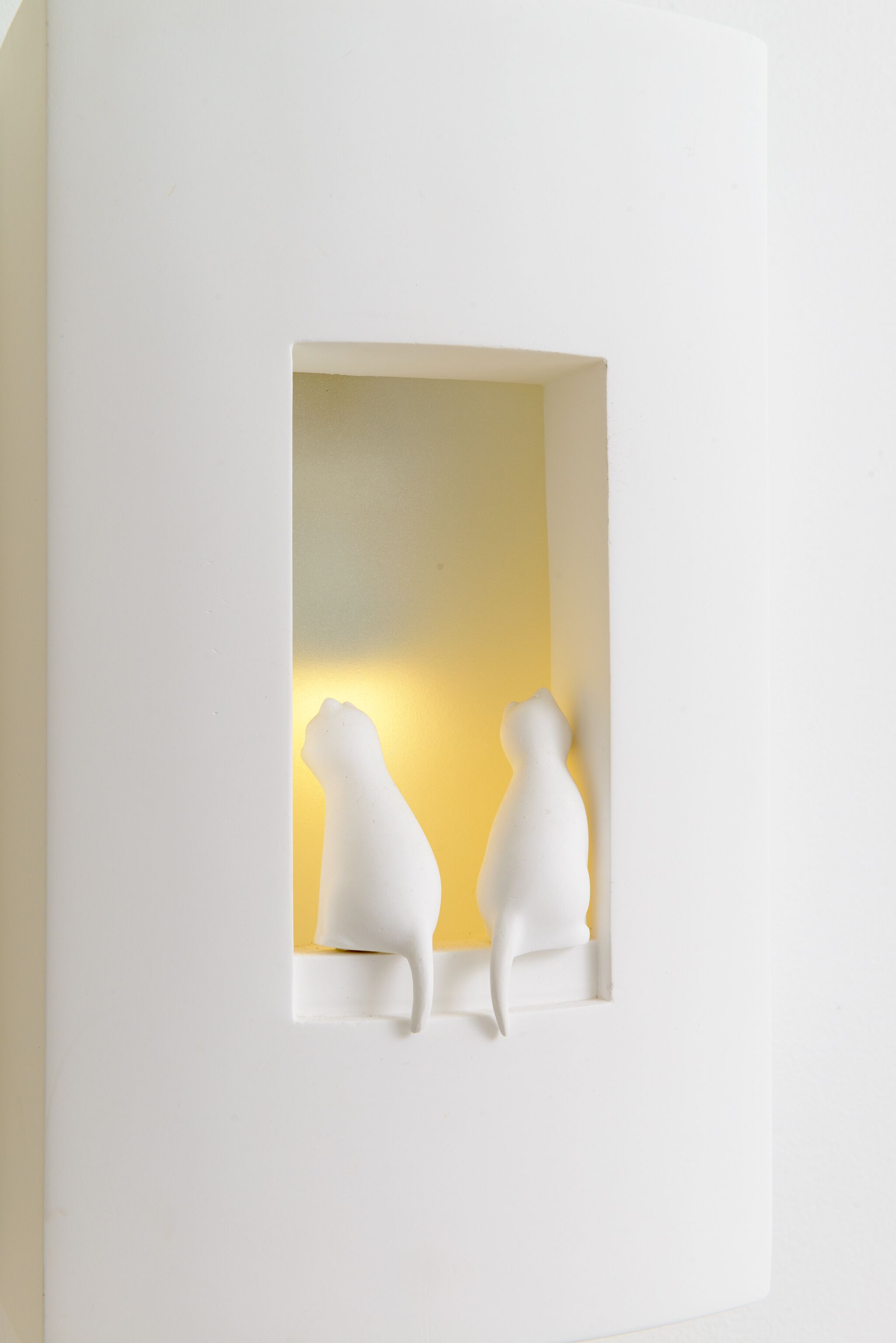 A white wall with a rectangular cutout containing two white, abstract sculptures.