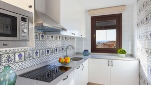 A kitchen with white cabinets, a microwave, a sink, and a window with a view.