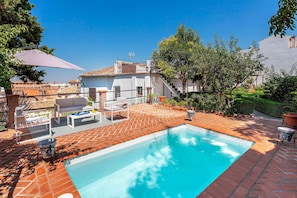 Une piscine dotée d’une terrasse carrelée, de mobilier d’extérieur et d’un escalier menant à un bâtiment.