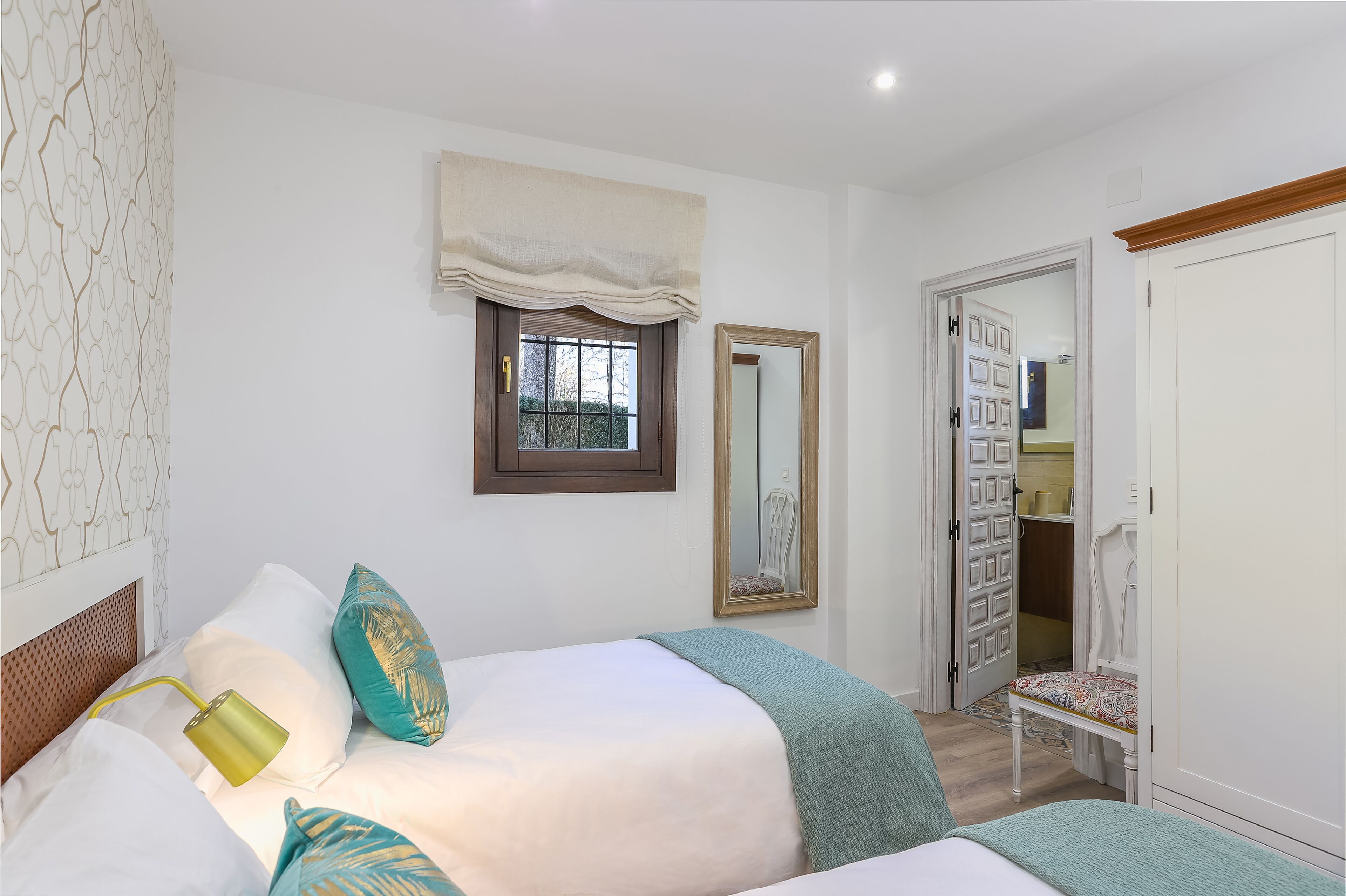 Un dormitorio con cama, mesita de noche, espejo y armario.