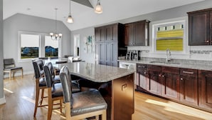 A modern kitchen with dark wood cabinets, a granite countertop, and a large island with bar stools.