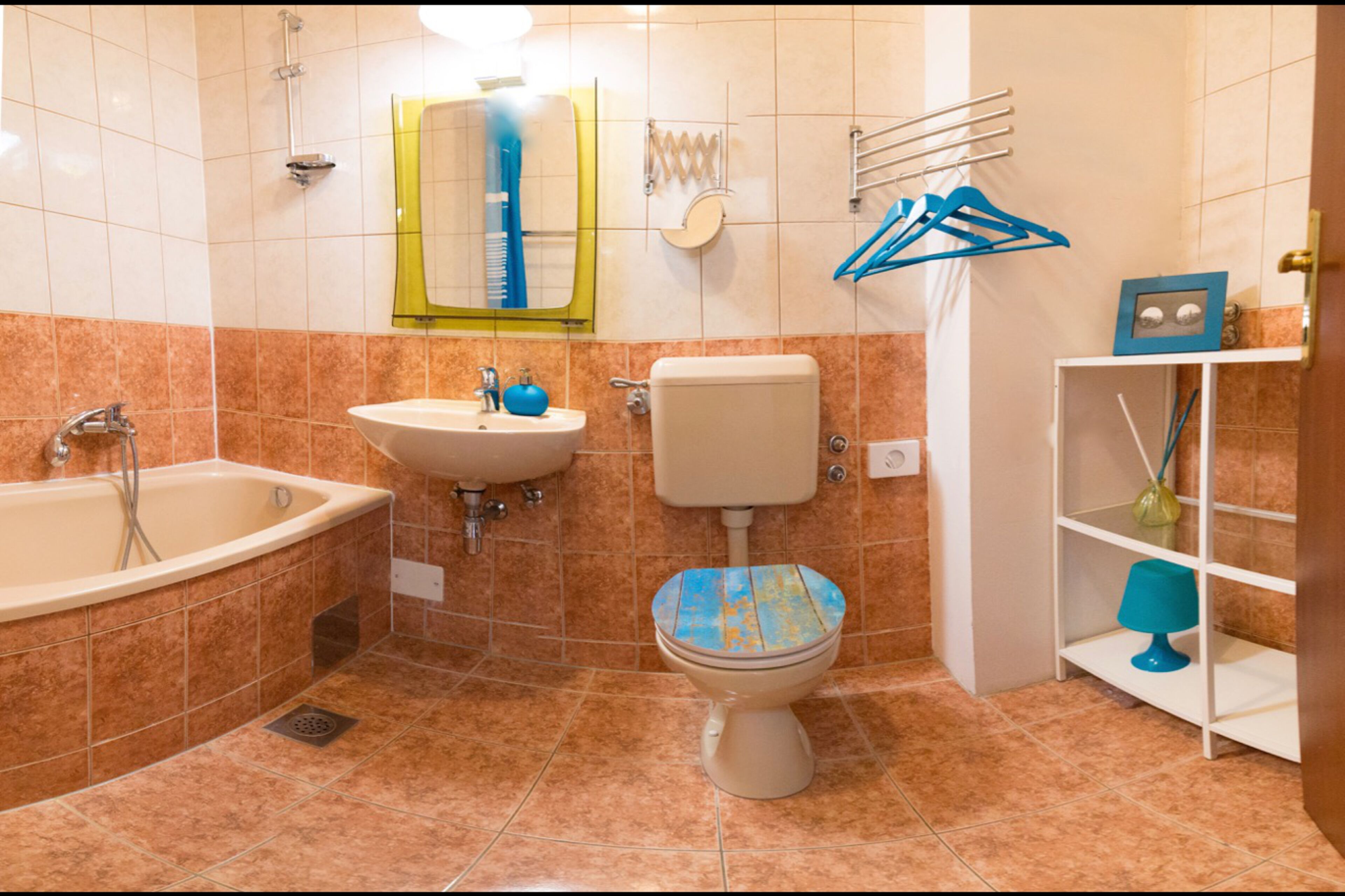 Casa de banho com banheira, pia, sanita e um armário com artigos de higiene pessoal.