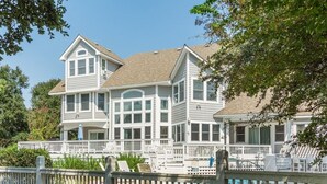 A two-story house with a large porch, multiple windows, and a swimming pool.