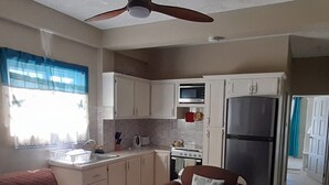 A compact kitchen with white cabinets, a microwave, a stove, and a refrigerator.