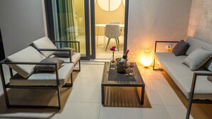 A modern living room with a sofa, armchairs, and a coffee table. There is a dining area visible through a glass door. - Villa Sara (Novalja)