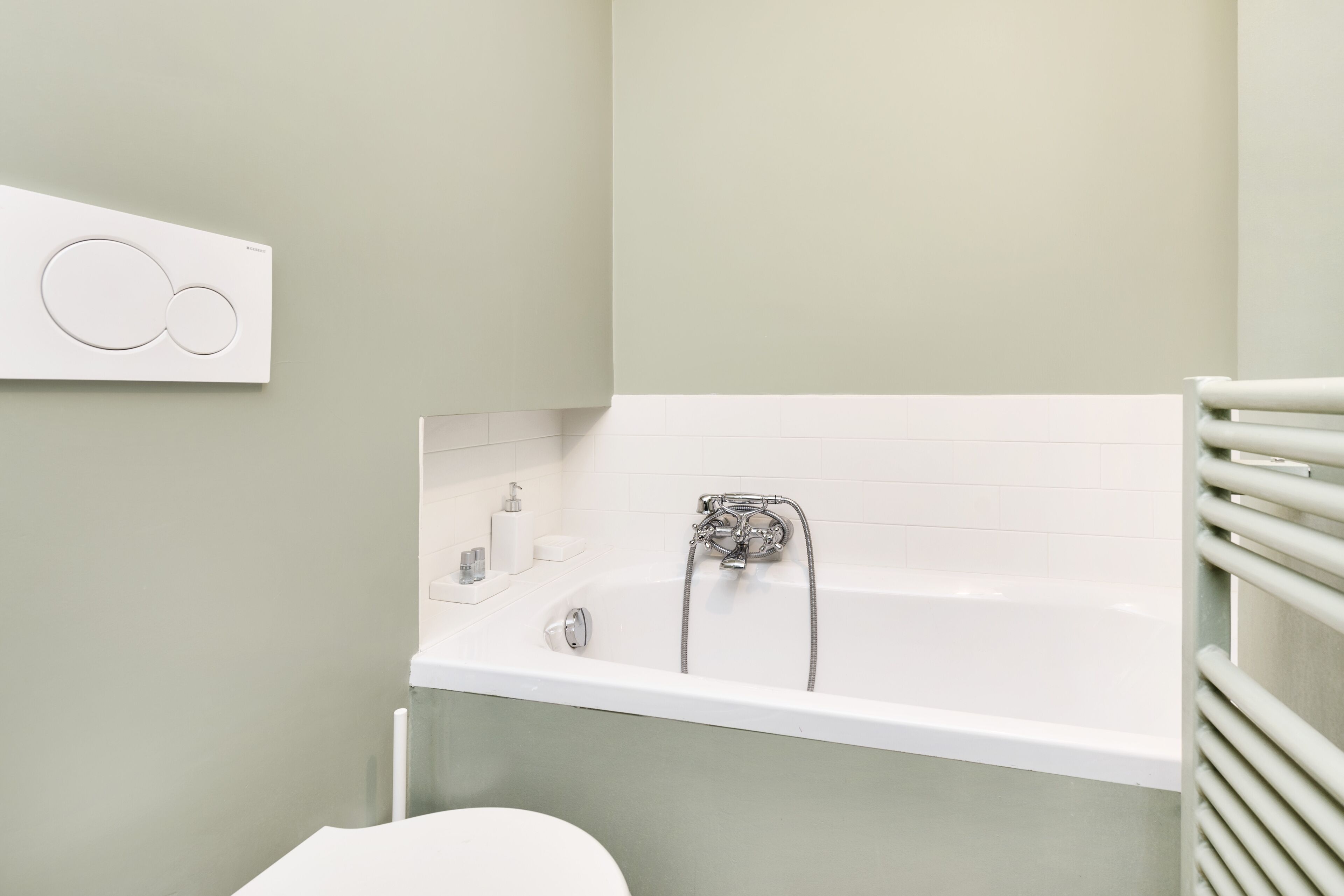 A bathroom with a white bathtub, a toilet, and a towel rack.