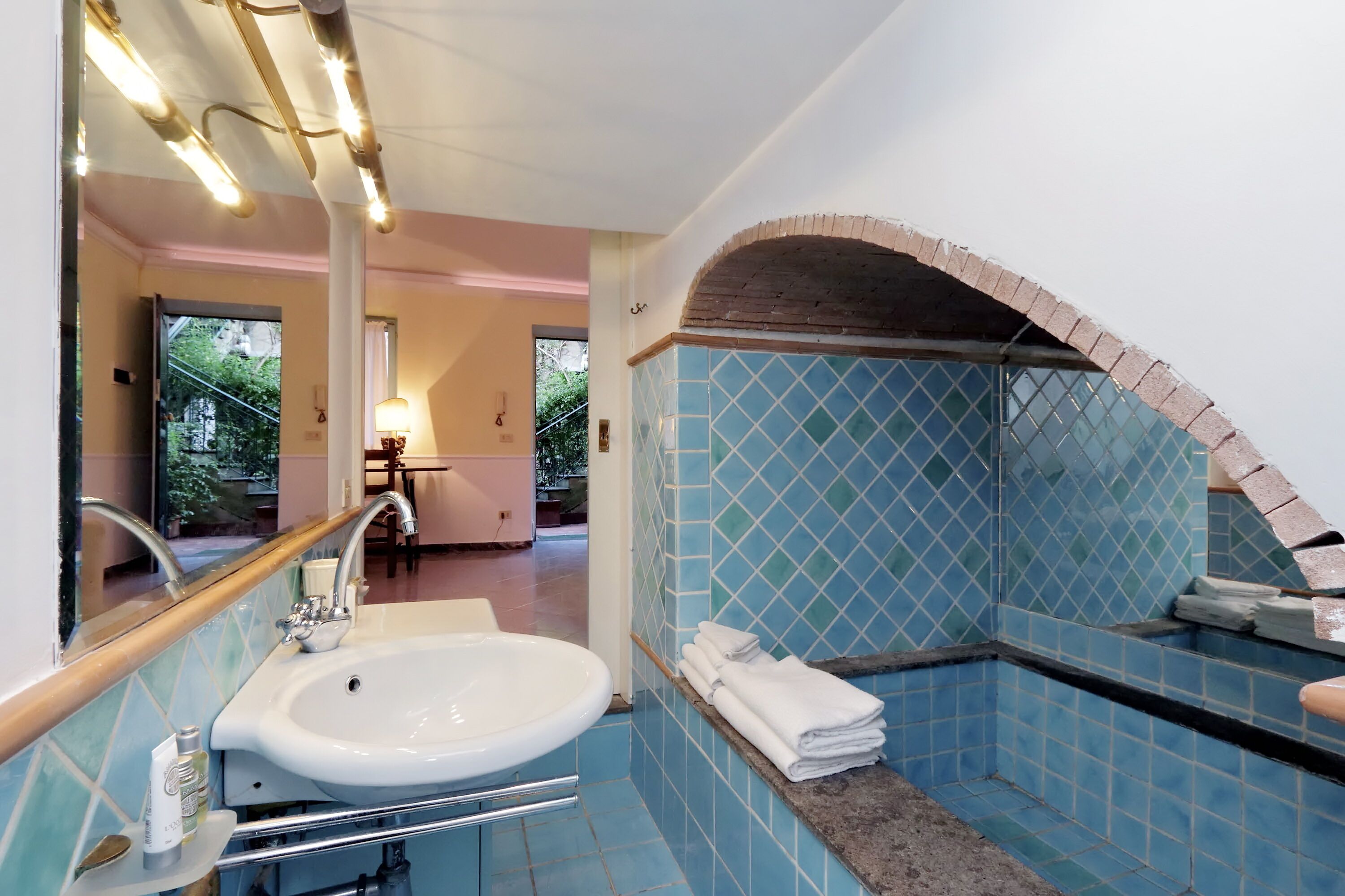 A bathroom with a sink, mirror, and blue-tiled walls.