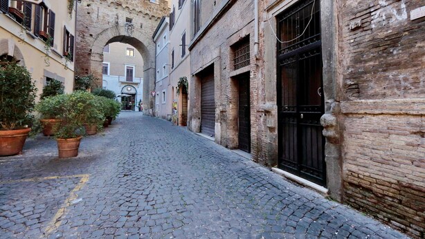 Una estrecha calle adoquinada flanqueada por edificios históricos, incluyendo un hotel con un letrero.