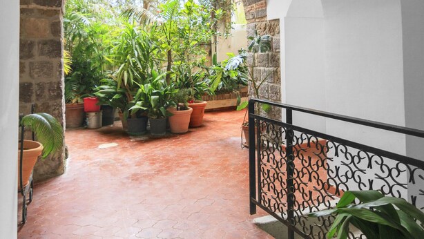 A covered walkway with terracotta tiles, potted plants, and a brick archway. - Seiano (Vico Equense)