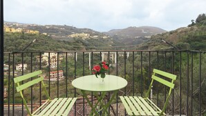 A balcony with a table and two chairs, overlooking a scenic landscape with buildings and hills. - Seiano (Vico Equense)