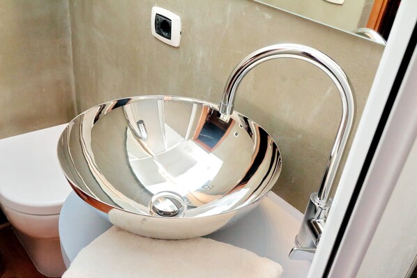 Une salle de bain moderne avec un lavabo chromé, des toilettes et un miroir.