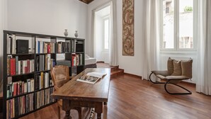 Een kamer met een houten tafel, boekenkasten, een stoel en een raam met gordijnen.