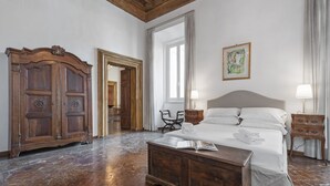 Een ruime slaapkamer met een groot bed, een houten garderobe en een spiegel.