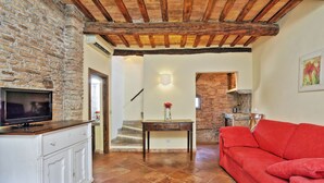 A living room with a red sofa, a white cabinet, a TV, and a staircase leading to another room. - Volpe (Rome)