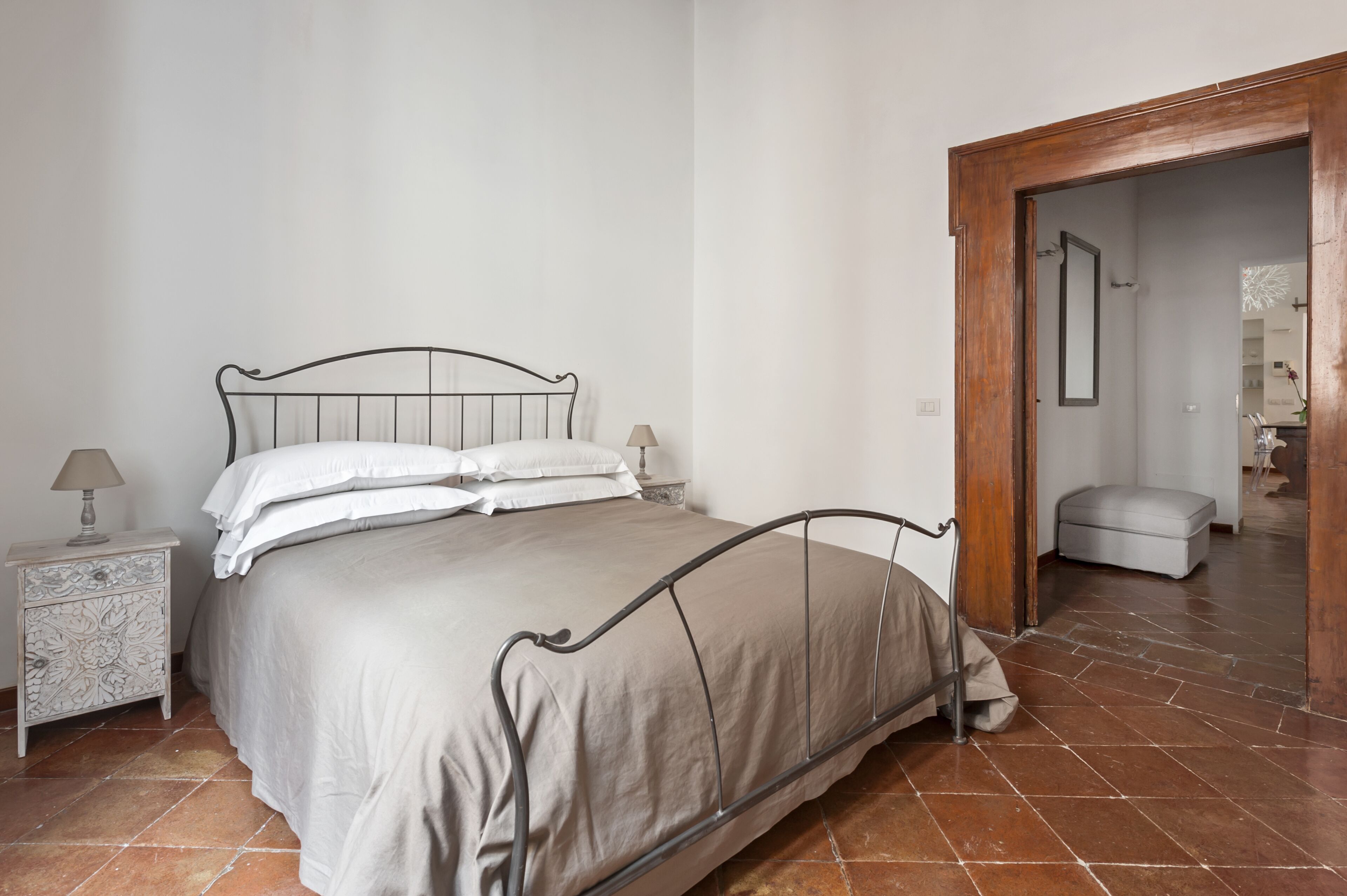A bedroom with a bed, nightstand, and a wooden door leading to another room.
