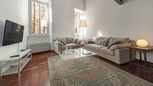 A modern living room with a flat-screen TV, two sofas, a coffee table, and a lamp. - Volpe grande (Rome)
