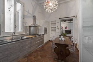 A modern kitchen with a central island, stainless steel appliances, and a dining area with clear chairs.