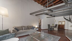 A modern living room with a sofa, coffee table, and a staircase. - Volpe grande (Rome)