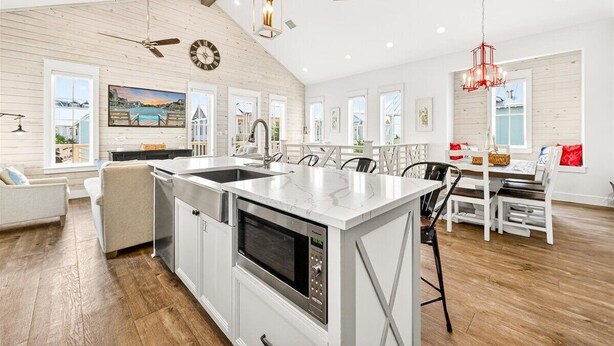 Una cocina moderna con una isla central, muebles blancos y un comedor con mesa y sillas.
