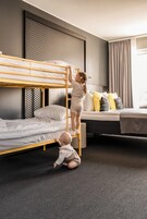 Camera con letto a castello, un bambino sale sulla scala e un altro gioca sul pavimento.