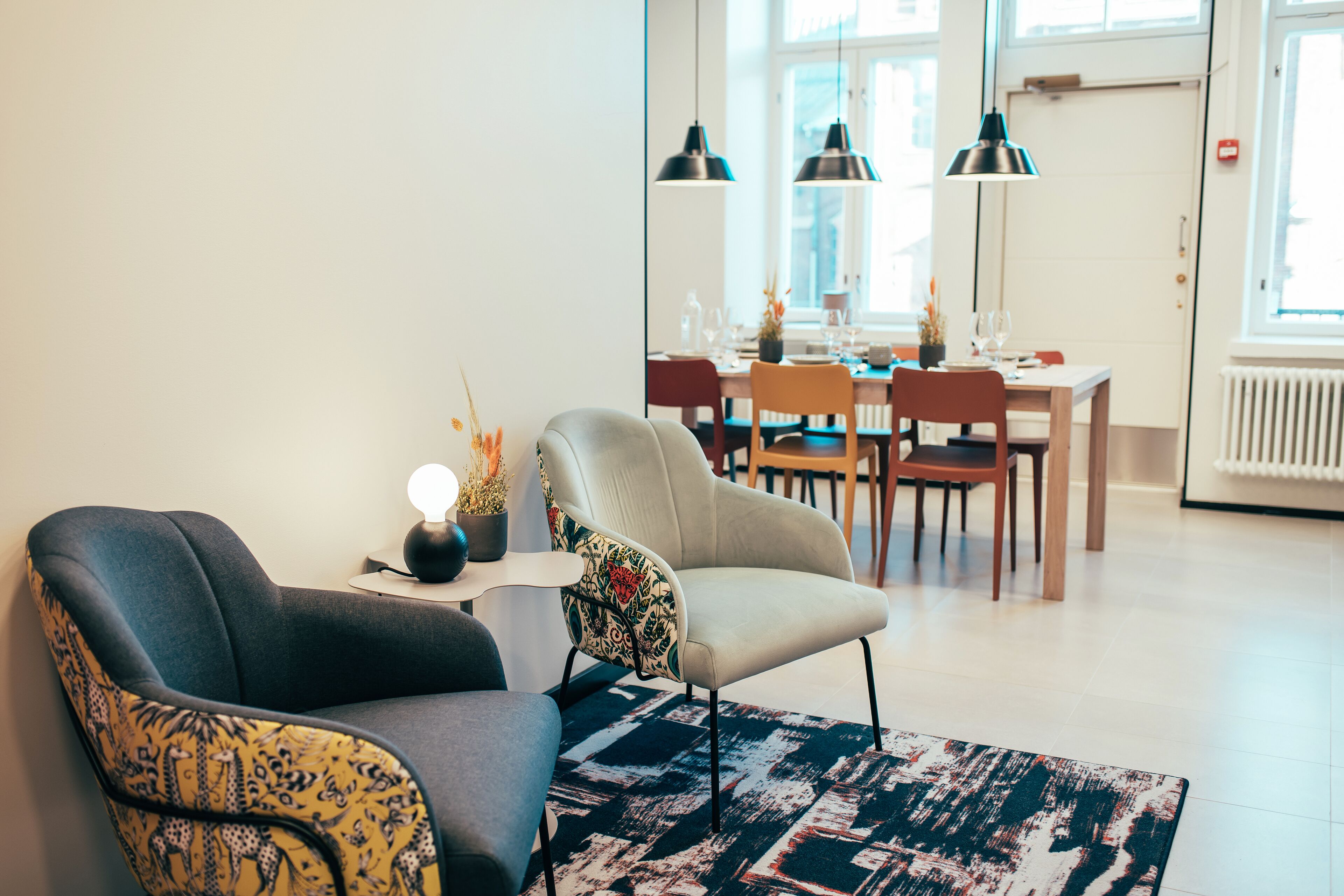 Una sala moderna con sofá, sillón y un comedor con mesa y sillas.